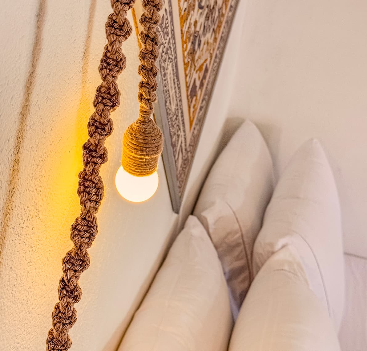 Luminária de macramê artesanal sobre a cama da Suíte Sertão