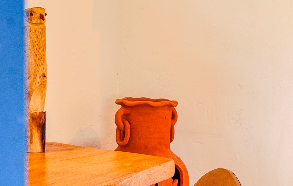 Vaso de cerâmica artesanal e escultura de coruja em madeira sobre mesa