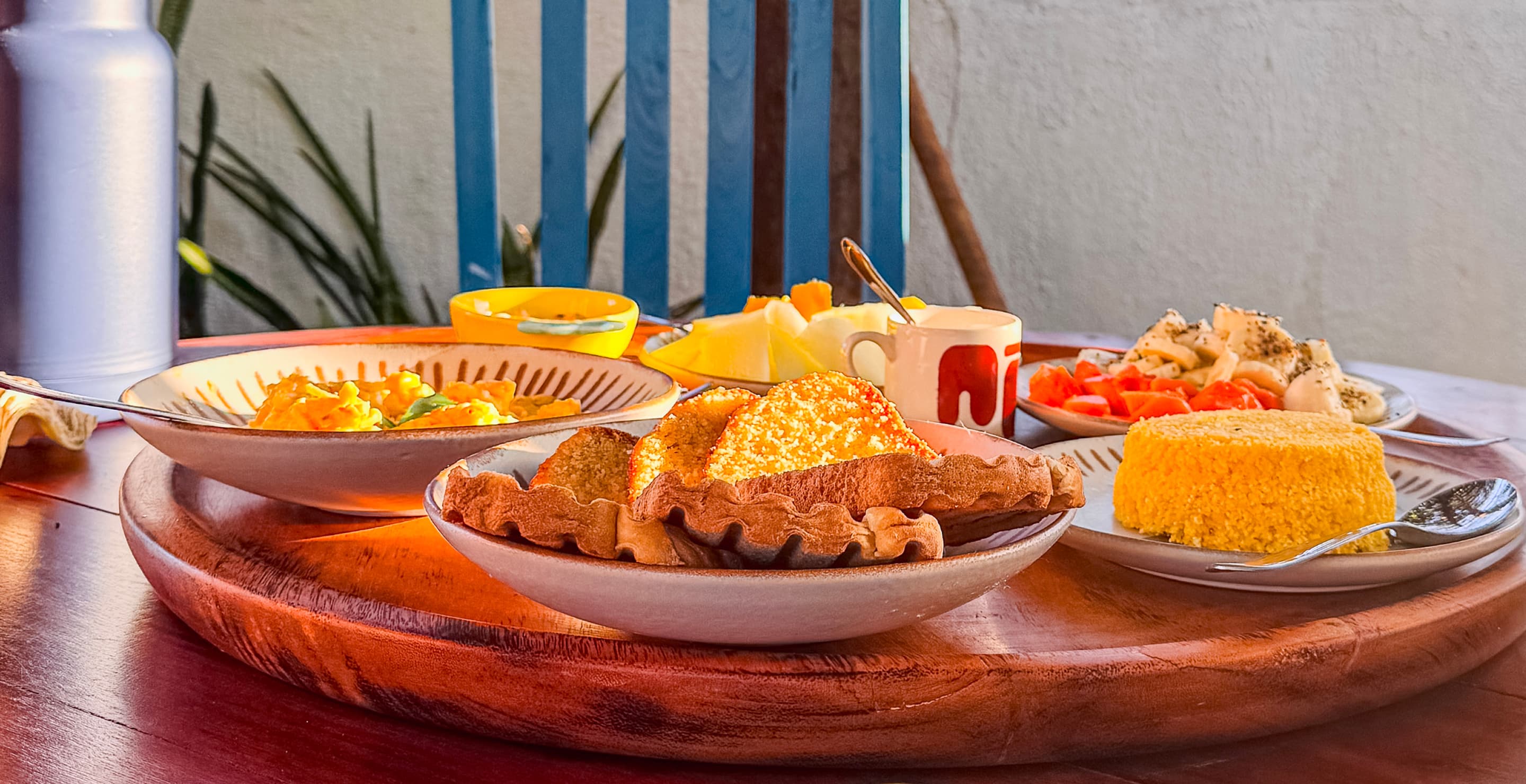 Café da manhã de autor servido em mesa redonda de madeira na Casa Mareser
